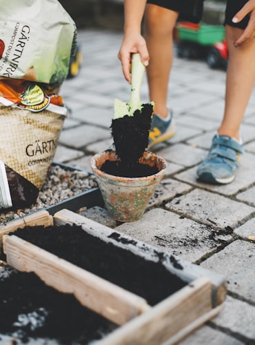 Child putting soil into a pot using a spade